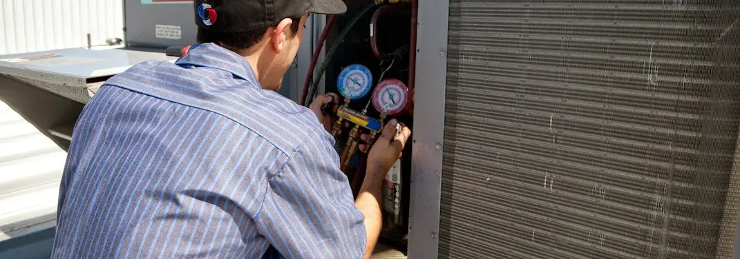 HVAC technician servicing a condenser unit in Four Corners